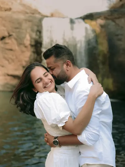 A spontaneous and happy moment of a kiss on the cheek by the waterfall. These candid shots are full of genuine emotion.