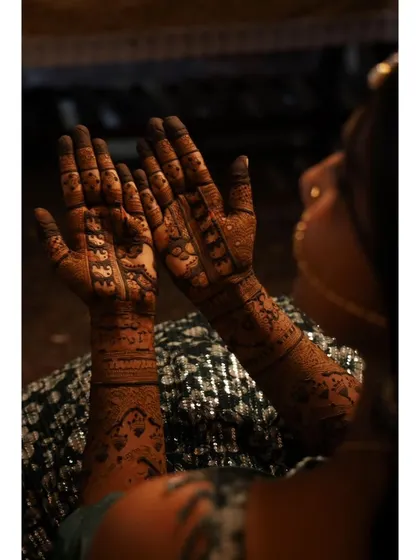 A view of the full bridal mehendi design from the back. The patterns flow from her palms to her arms, creating a complete and stunning work of art.