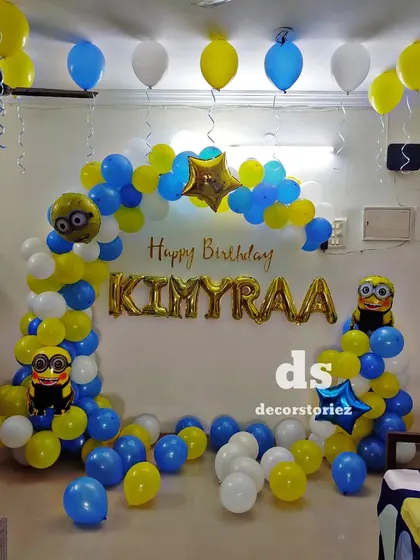 A fun and playful Minions theme birthday decoration. The classic blue and yellow balloon arch is decorated with Minion character foils, perfect for a cheerful and mischievous party vibe.