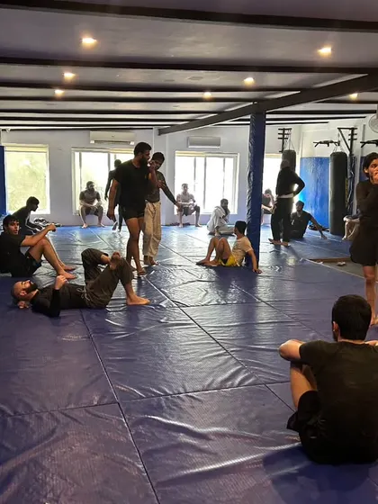 The mat is a space for learning and growth. Here, students are scattered across the gym, some rolling, some resting, and some discussing techniques after a round.