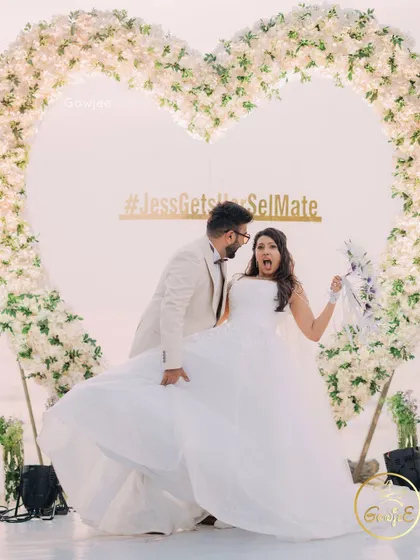 A fun and candid moment of the couple at their beach wedding reception, in front of a beautiful heart-shaped floral arch.