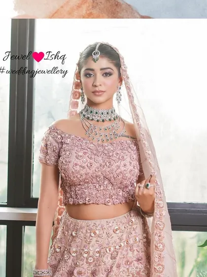 A glamorous bridal look featuring a stunning layered diamond and emerald necklace set against a delicate pink lehenga. This is for the bride who wants to feel both romantic and regal.