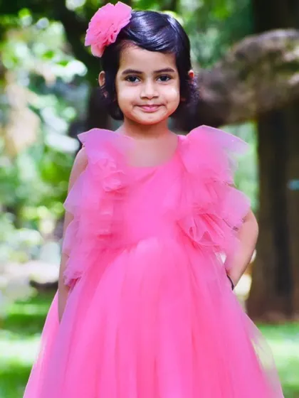 This little girl looks like a real-life doll in her pink frilly gown and matching hair accessory.