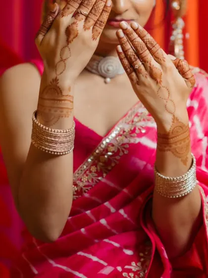An artistic shot of the bride, with her mehndi-adorned hands partially covering her face. This portrait is both mysterious and beautiful.
