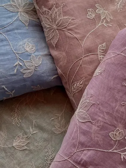 A collection of our embroidered Mul Chanderi fabrics in various pastel shades, all featuring the same delicate white floral embroidery.