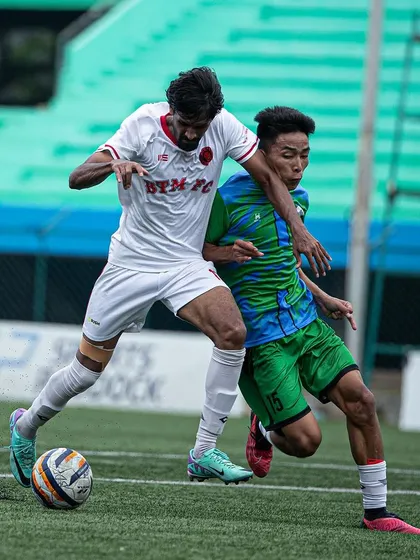 A BTM FC player shields the ball from an opponent, showcasing the physical strength and determination required in the A-Division.