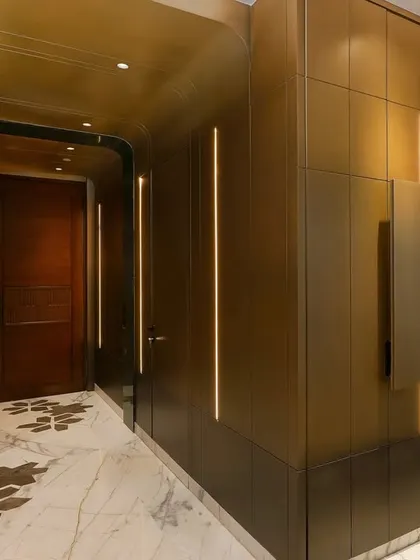 This entryway shot reveals a cleverly concealed bar unit integrated into the brass wall paneling. It's a perfect example of our ability to blend high-end functionality with subtle, intriguing design.