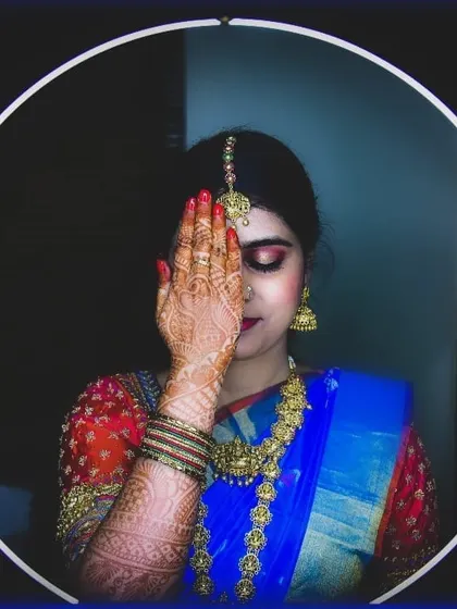 A creative shot highlighting the intricate henna and the bold eye makeup. The ring light frames her face, showing the details of her maang tikka and smokey eyeshadow.