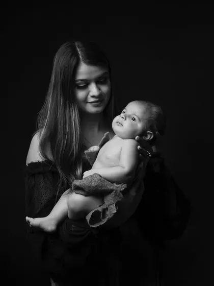A mother gazes at her newborn, a world of love in her eyes. This dramatic, low-key black and white portrait is full of emotion.