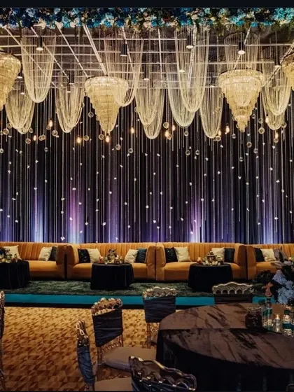 A luxurious lounge area for a cocktail night. The decor features a dark, moody backdrop with hanging drapes and chandeliers, and comfortable seating for guests.