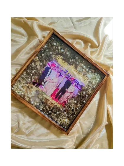A top-down view of the anniversary varmala preservation, showing the careful arrangement of photos and flowers that tell a story of decades of love.