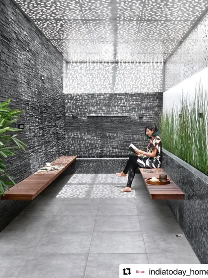 The lower terrace is a tranquil, semi-enclosed space with slate-clad walls and a perforated metal sheet roof. The filtered sunlight creates dynamic patterns on the walls and floor, making it a magical spot for reading or quiet contemplation.