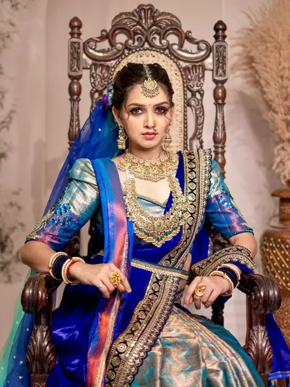 A powerful portrait in the peacock-inspired look. The model is seated on a throne, and the drape adds to the royal and commanding presence.