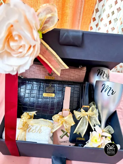 A sophisticated couple's hamper with personalized 'Mr & Mrs' travel accessories, wine glasses, and towels, all packed in a sleek black box.