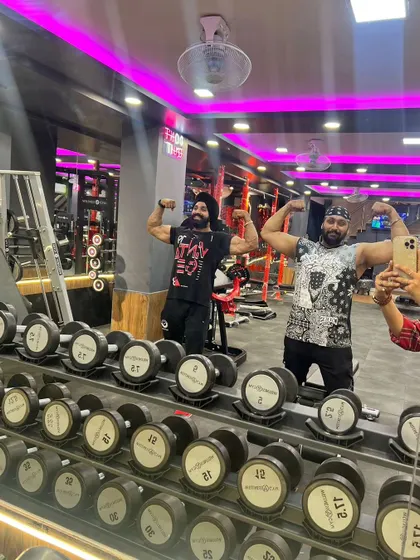 Hitting a double bicep pose with a friend in the gym. Surrounding yourself with people who share your drive is key to staying motivated.