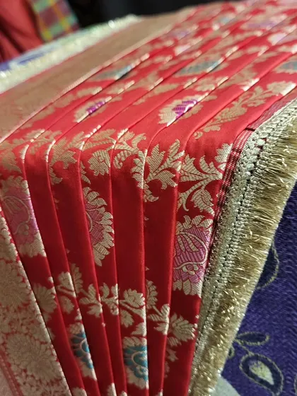 A detailed shot of the crisp pleats on the red bridal saree.