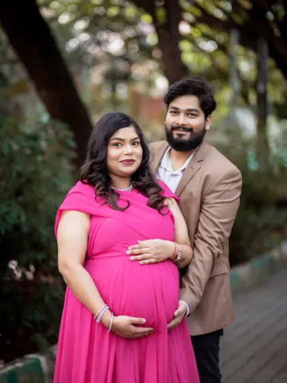 A beautiful couple's portrait taken outdoors, surrounded by greenery. The vibrant pink dress adds a wonderful pop of color to this loving moment.