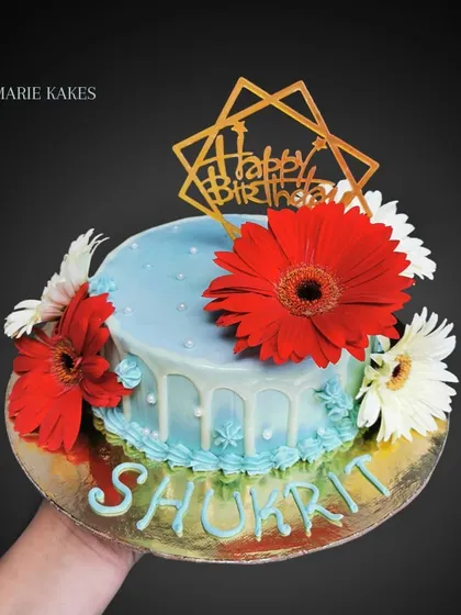 A simple and fresh Funfetti cake. This design features a white chocolate drip and is decorated with bright red and white fresh gerbera daisies.