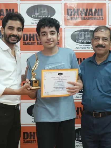 A teacher and a senior member present an award to a student.