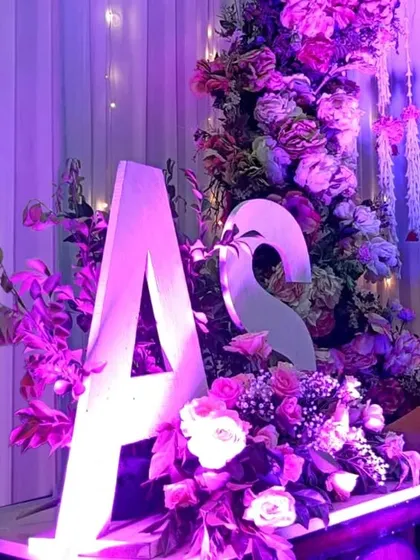 Large, illuminated initials of the couple, nestled in a bed of purple flowers. This is a fantastic way to personalize the stage or entrance area and create a unique focal point.