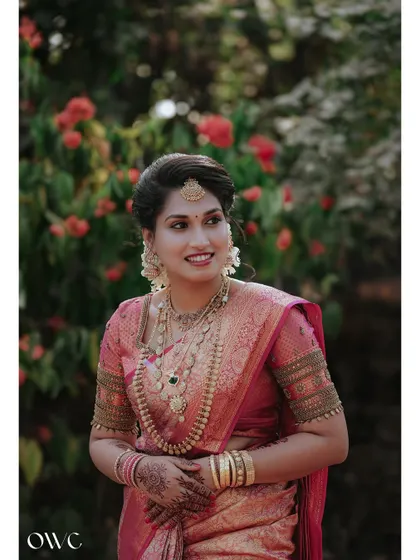 A radiant portrait of a bride in a pink Kanjeevaram saree, her smile genuine and happy.