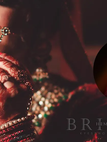 A close-up bridal portrait focusing on the intricate details of her nath and henna-adorned hand. The soft lighting and shallow depth of field create a beautiful, intimate feel.