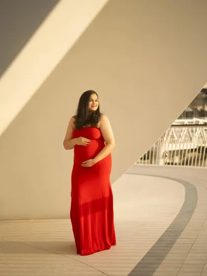 A simple and joyful outdoor portrait. The mom-to-be’s happy expression and the way she holds her bump convey a sense of peaceful anticipation.