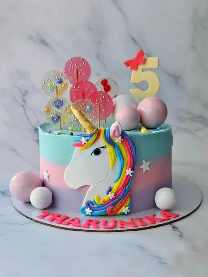 Hey, Unicorn! A colorful unicorn cake for Tharunika's 5th birthday. This vanilla cake features a unicorn cookie, lollipops, and a beautiful pastel rainbow frosting.