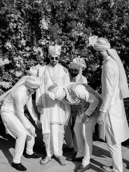 The groom's friends helping him get ready. This black and white shot captures the friendship and support system on the big day.