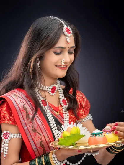 A serene portrait of a woman looking down at a decorative thali. This shot focuses on the intricate details of her sugar jewelry and the traditional elements of the festival.