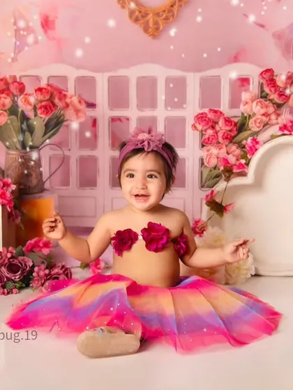 A fun and whimsical shot of a little girl in a colorful tutu skirt against a beautiful pink floral backdrop.