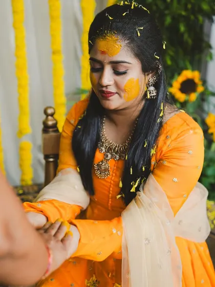 A close-up of the bride during her Haldi ceremony. The decor includes sunflowers and marigolds, perfectly matching the bright yellow theme of the event.