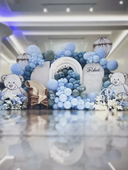 An elaborate teddy bear themed setup in shades of blue and white. The backdrop features large illustrated bears and a wicker chair for the birthday boy, creating a grand photo opportunity.
