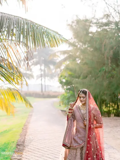 A bride walks along a path in Goa, the morning sun filtering through the palm trees, creating a soft, dreamy portrait.