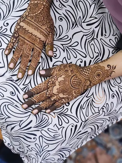 A beautiful party henna design with a mix of styles. One hand has a traditional mandala, while the other features a more modern pattern.