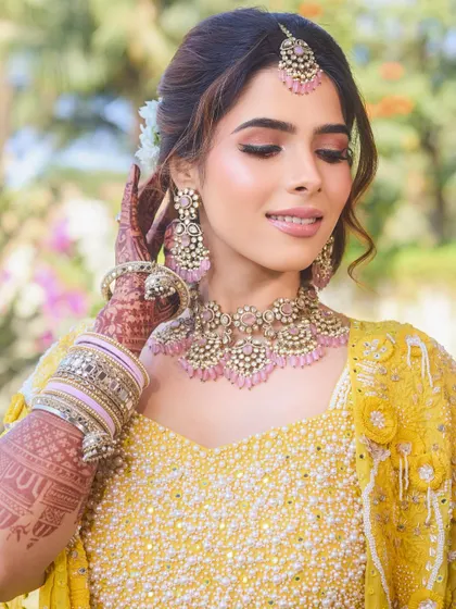 A close-up on the bride's radiant Haldi makeup. The soft pink eyeshadow and glowing skin create a look that is both elegant and joyful.