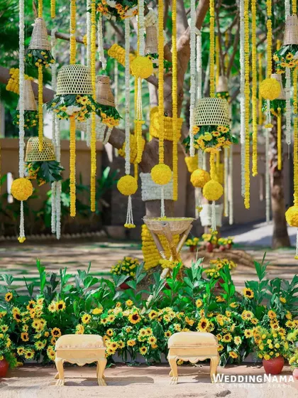 A close-up of the haldi backdrop, showing the intricate details of the hanging floral baskets and the lush sunflower base.