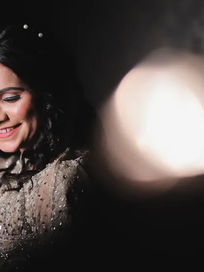 An artistic bridal portrait using lens flare and bokeh for a dreamy effect. The focus is on her happy, candid expression as she gets ready for her big day.