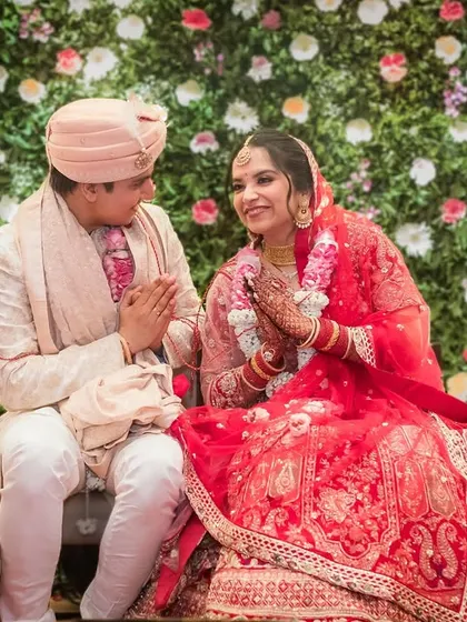 A sweet, seated portrait of the couple during their wedding. They share a look of mutual respect and affection, their hands joined in prayer.