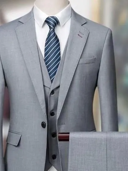 The same light grey three-piece suit, showing how it can be styled with a striped tie for a classic business look.