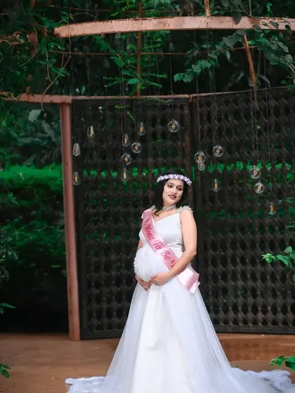 A mom-to-be wearing a "Mom To Be" sash with the white maternity gown. This look is perfect for baby showers and announcement photoshoots.