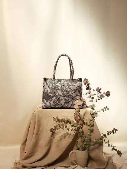 An earthy, rustic still life featuring a patterned tote bag. The use of natural linen fabric and dried eucalyptus creates a soft, organic, and sophisticated mood.