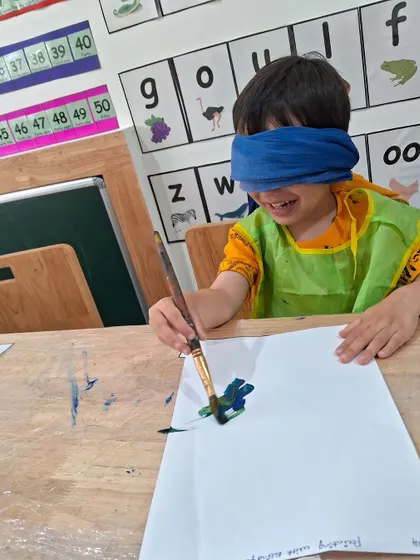 A smile of delight shows how much fun this boy is having with our blindfold painting challenge. It’s a joyful way to build confidence and try something new.