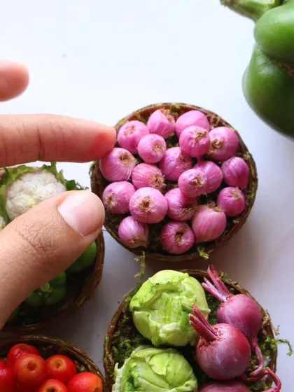 A close-up of a basket of miniature onions, showing the delicate roots and vibrant color.