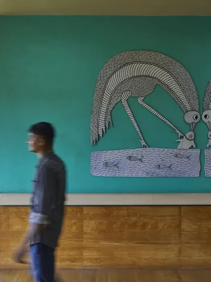 A man walks past a large Gond art mural in the JSW Sanjeevani Hospital. Integrating art from local traditions was key to making the hospital feel less institutional and more like a welcoming community space that celebrates regional culture.