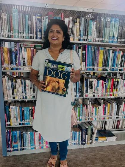 My passion for dogs goes beyond just caring for them. I'm always learning, here at a library with a comprehensive book on dogs to deepen my knowledge.