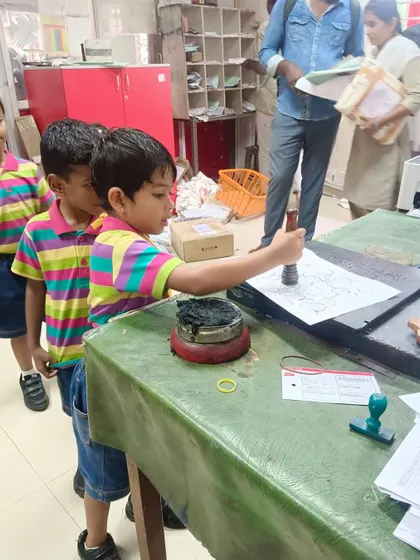 Another student tries his hand at stamping, an engaging part of the post office tour.