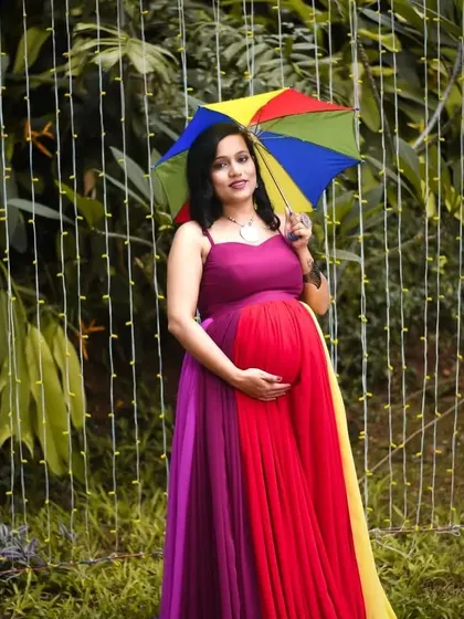 We love adding a pop of color to our maternity shoots. This vibrant, multi-colored flowing gown looks incredible in an outdoor garden setting, especially with fun props like this rainbow umbrella.