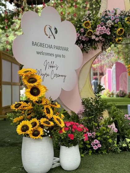 A welcome sign for 'Nikki's Mayra Ceremony', surrounded by bright and cheerful sunflowers.