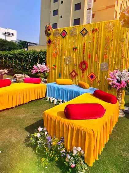 A colorful and casual seating arrangement for a Mehendi party. I used low divans with bright cushions and a vibrant backdrop with traditional hangings to create a relaxed and festive vibe.